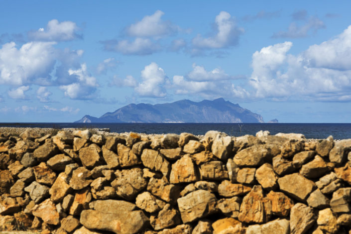 Immagine stampata su tela o carta fine art di Marettimo vista da Favignana con muretto di pietre in primo piano